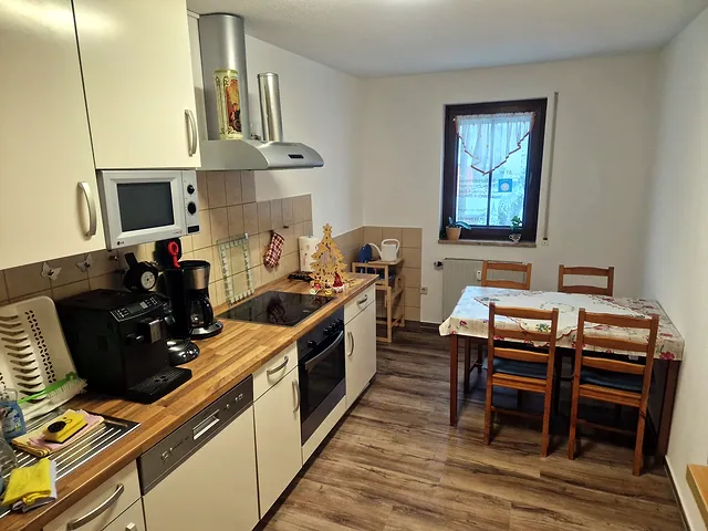 Separate Einbauküche mit Kaffeevollautomat, Ceran-Kochfeld und Esstisch am Fenster
